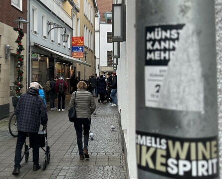 Eine Seitengasse in Münster wo viele Leute auf ihre Bestellung warten die sie bei der HotDog Station gemacht haben. 